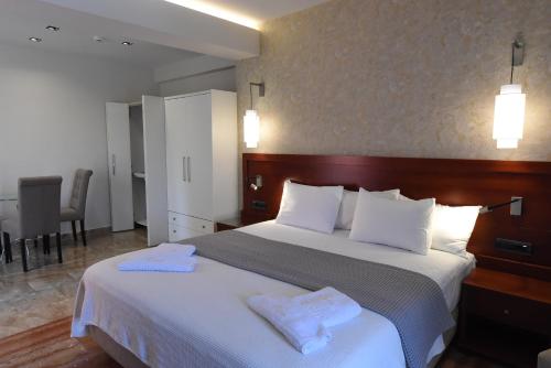 a bedroom with a large bed with two towels on it at Viaros Hotel Apartments in Tolo