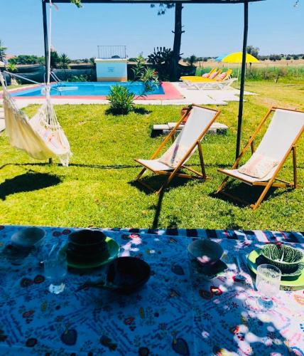 two lawn chairs and a hammock in the grass at Monte Ramos in Ferreira do Alentejo