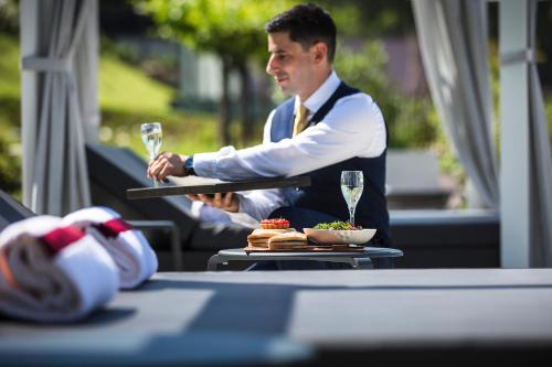a man holding a glass of wine at a table at Hôtel L'Incomparable Aix-Les-Bains in Tresserves