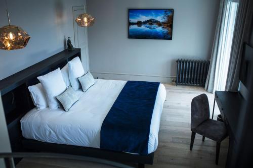 a bedroom with a bed with white sheets and a blue blanket at Hôtel L'Incomparable Aix-Les-Bains in Tresserves
