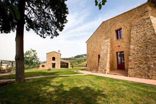 an exterior view of a stone building with a tree at Fattoria Le Fonti in Poggibonsi