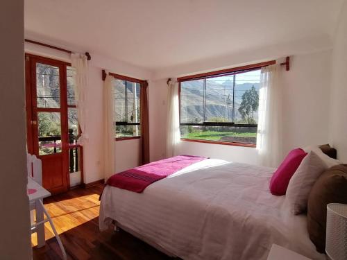 a bedroom with a large bed and two windows at Hostal Chaska Wasi in Ollantaytambo