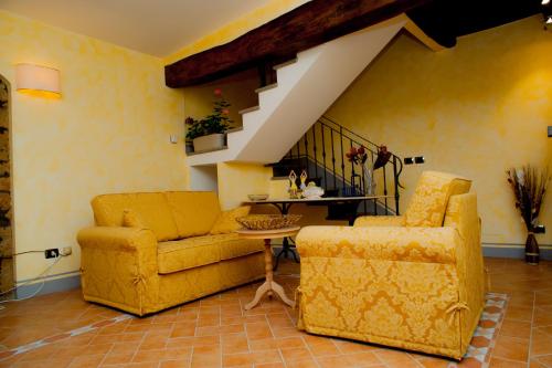 a living room with two chairs and a couch and stairs at Casa Flora in Civitella dʼAgliano