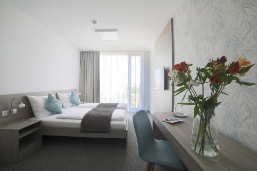 a bedroom with a bed and a table with a vase of flowers at Hotel HENDI CENTRUM in Piešťany