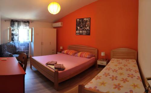 a bedroom with orange walls and a bed and a chair at Rooms Raulo in Split