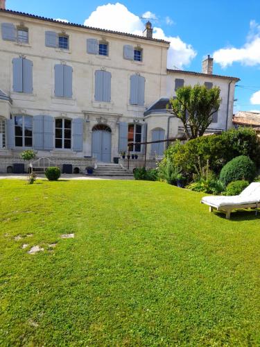 a large house with a green lawn in front of it at Le Jardin des Anges in Saint-Jean-dʼAngély