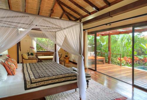 a bedroom with a canopy bed and a balcony at Nayara Springs - Adults Only in Fortuna