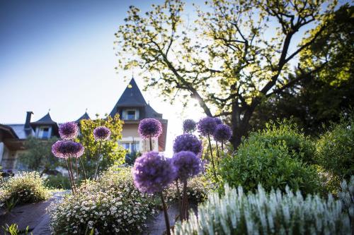 a garden with purple flowers in front of a house at Hôtel L'Incomparable Aix-Les-Bains in Tresserves