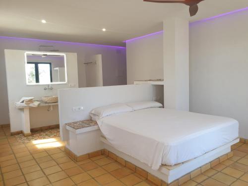 1 dormitorio con cama blanca y espejo en Masia La Candelera, en L'Ametlla de Mar