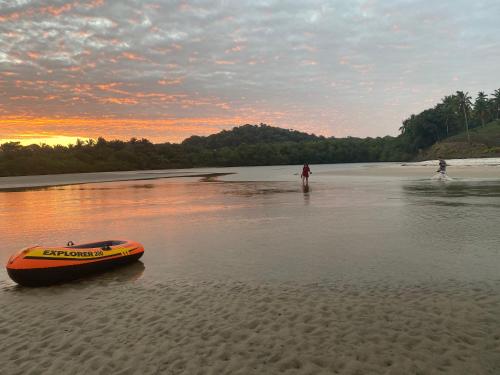 an orange boat sitting on a beach with people in the water at Pousada e Restaurante Palomar in Ilhéus