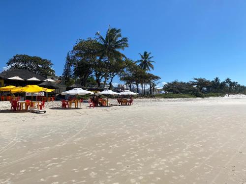 a beach with tables and chairs and umbrellas at Pousada e Restaurante Palomar in Ilhéus
