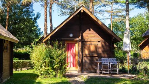 a small cabin with a red door and a table and chairs at Le Domaine du Cerf Blanc in Carentoir