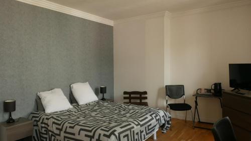 1 dormitorio con 1 cama con edredón blanco y negro en La Boule d'Or, en Bourganeuf