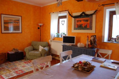 een woonkamer met oranje muren en een tafel en stoelen bij Casa intera tra le colline e le vigne del Dolcetto in Rocca Grimalda