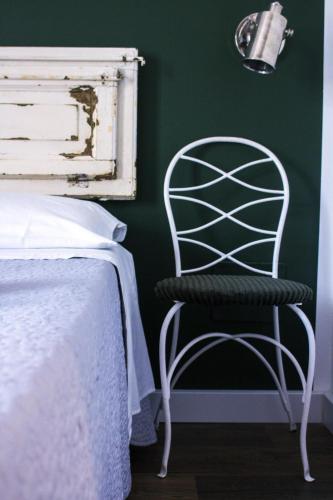 a white chair in a bedroom with a green wall at Cialoma B&B in Palermo