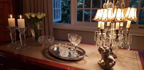 a table with a chandelier and glasses on it at The Great Gatsby Houghton in Johannesburg