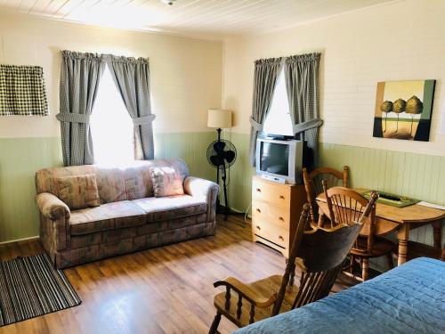 a living room with a couch and a tv at Green Gables Bungalow Court in Cavendish