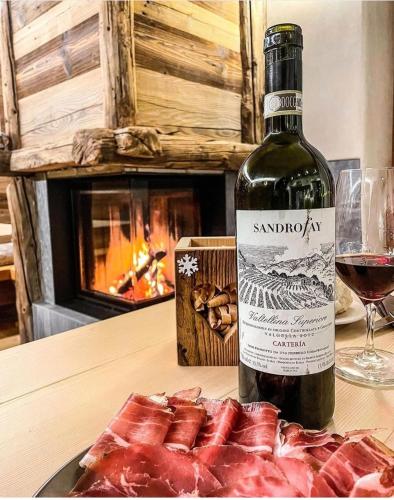 a bottle of wine next to a plate of meat at Chrys b&b in Valfurva
