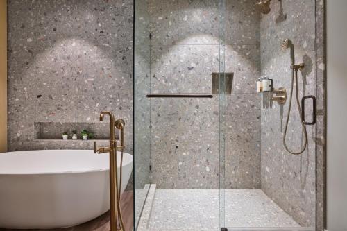 a bathroom with a shower with a tub and a sink at Mission Pacific Beach Resort, part of JdV by Hyatt in Oceanside