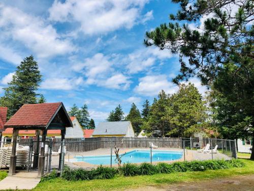 a swimming pool with a fence around it at Green Gables Bungalow Court in Cavendish
