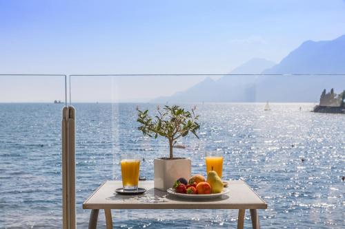 a table with a plate of fruit and orange juice at Hotel Val Di Sogno - Adults Only in Malcesine
