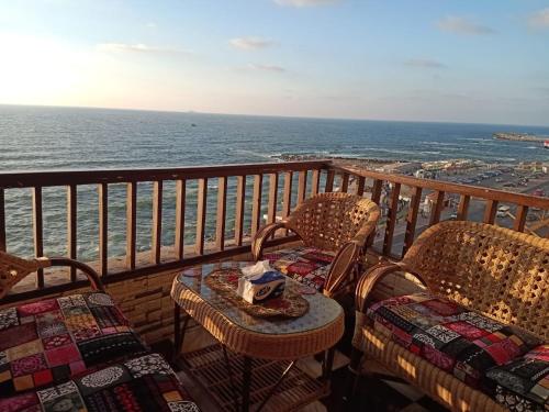 sporting sea view two bedroom appartement في الإسكندرية: طاولة وكراسي على شرفة مطلة على المحيط