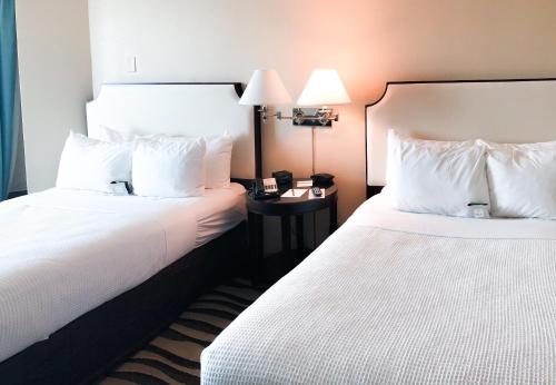 two beds in a hotel room with white pillows at Fort Pontchartrain Detroit, a Wyndham Hotel in Detroit