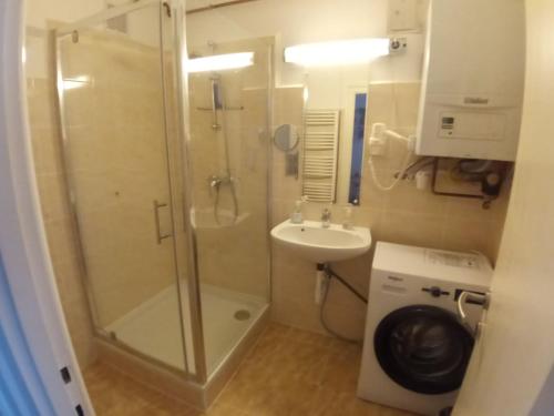 a bathroom with a shower and a sink and a washing machine at Deák apartmanok in Sopron