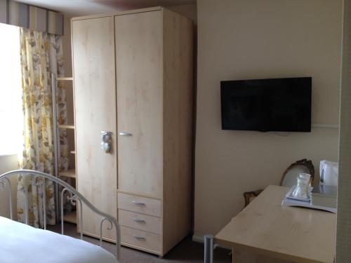 um quarto com uma cama e uma cómoda com uma televisão em New Masons Arms em Leeds