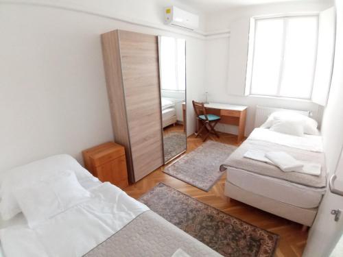 a small bedroom with two beds and a mirror at Deák apartmanok in Sopron