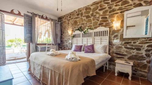 a bedroom with a large bed in a stone wall at Villa Malaga con Jacuzzi Piscina vallada Barbacoa By AndaraHolidays in Sayalonga