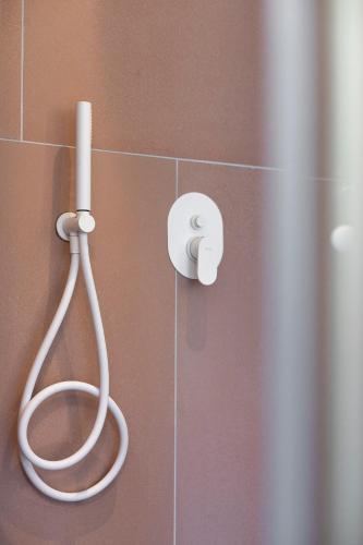 a bathroom with a shower with a white hose at Mandraki Village Boutique Hotel in Koukounaries