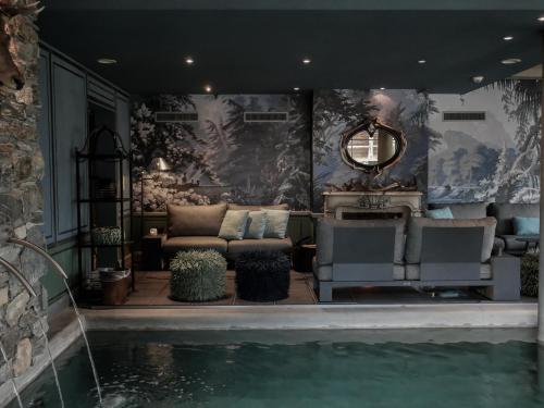 a living room with a couch and a swimming pool at Hôtel Bella Tola & SPA in Saint-Luc