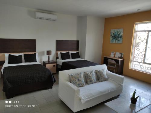 ein Hotelzimmer mit 2 Betten und einem Sofa in der Unterkunft Hotel del Bosque in Torreón