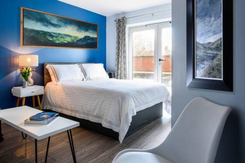 a blue bedroom with a bed and a window at Luxury City Apartment Underground Parking 5* in Belfast