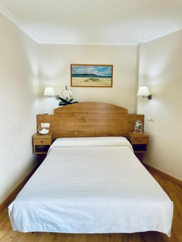 a bedroom with a large white bed with two night stands at Hostal Casa Isabel in Portonovo