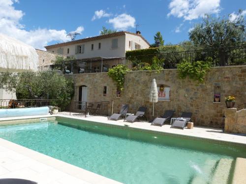 a swimming pool with chairs next to a building at Mas De La Coste in Fayence