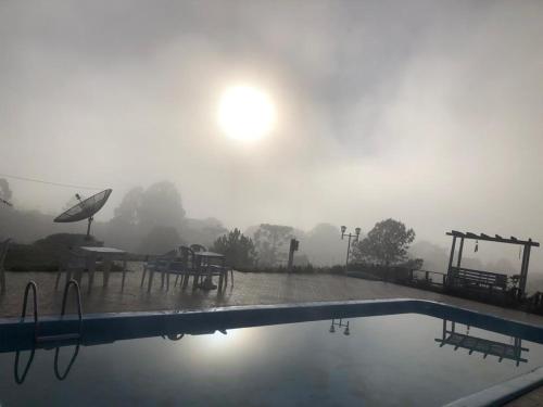 una piscina bajo la lluvia con mesa y sombrilla en Pousada Fazenda da Invernada, en Urubici