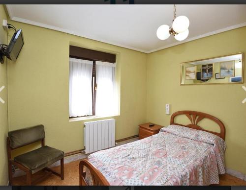 a bedroom with a bed and a chair and a window at Pensión Minibar in Zarátamo