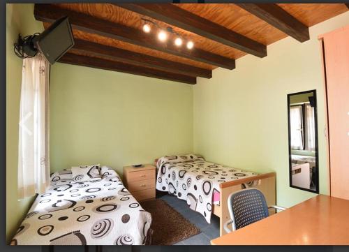 Habitación con 3 camas, mesa y espejo. en Pensión Minibar en Zarátamo