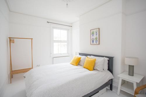 um quarto branco com uma cama com almofadas amarelas em Elegant York House - on a beach road, sleeps 12, with sea views em Worthing