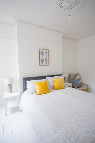 a white bedroom with a bed with two yellow pillows at York House in Worthing