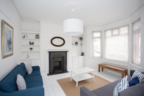 a living room with a blue couch and a fireplace at Elegant York House - on a beach road, sleeps 12, with sea views in Worthing