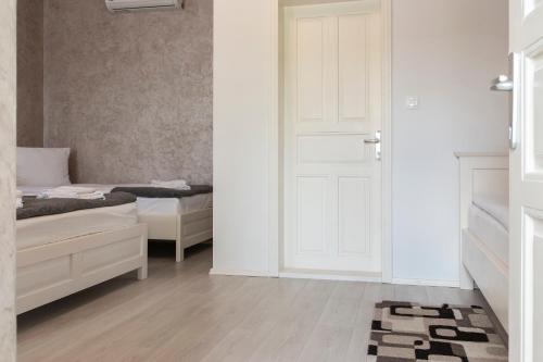a bedroom with two beds and a door and a rug at Airport Wanderer Inn - Vándor fogadó in Vecsés