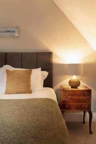 a bedroom with a bed and a wooden night stand at Bridge Street Townhouse in Kenmare