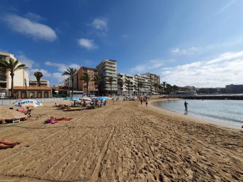 plaża z ludźmi leżącymi na piasku i wodzie w obiekcie Apartamento Belsol w mieście Torrevieja