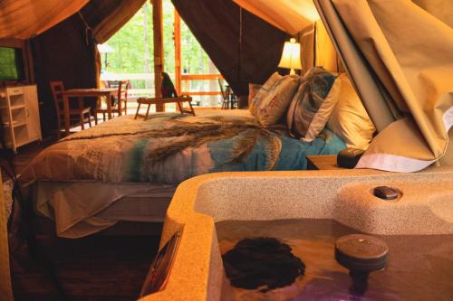 a bedroom with a bed and a tub in a tent at Country Road Cabins in Hico