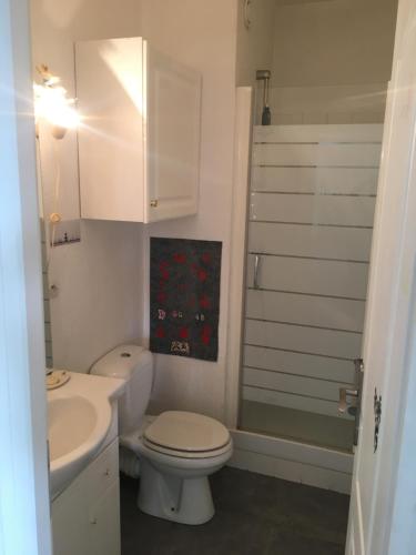 une salle de bain avec des toilettes blanches et un lavabo dans l'établissement L'aubaine, à Saint-Aubin-sur-Mer