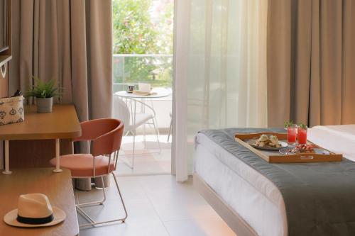a hotel room with a bed with a tray of food on it at Mandraki Village Boutique Hotel in Koukounaries