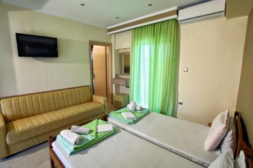 a hotel room with two beds and a couch at Sun Studios Pieria in Paralía Skotínis